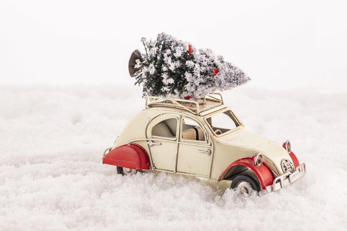 Toy car with a christmas tree on the roof in snow