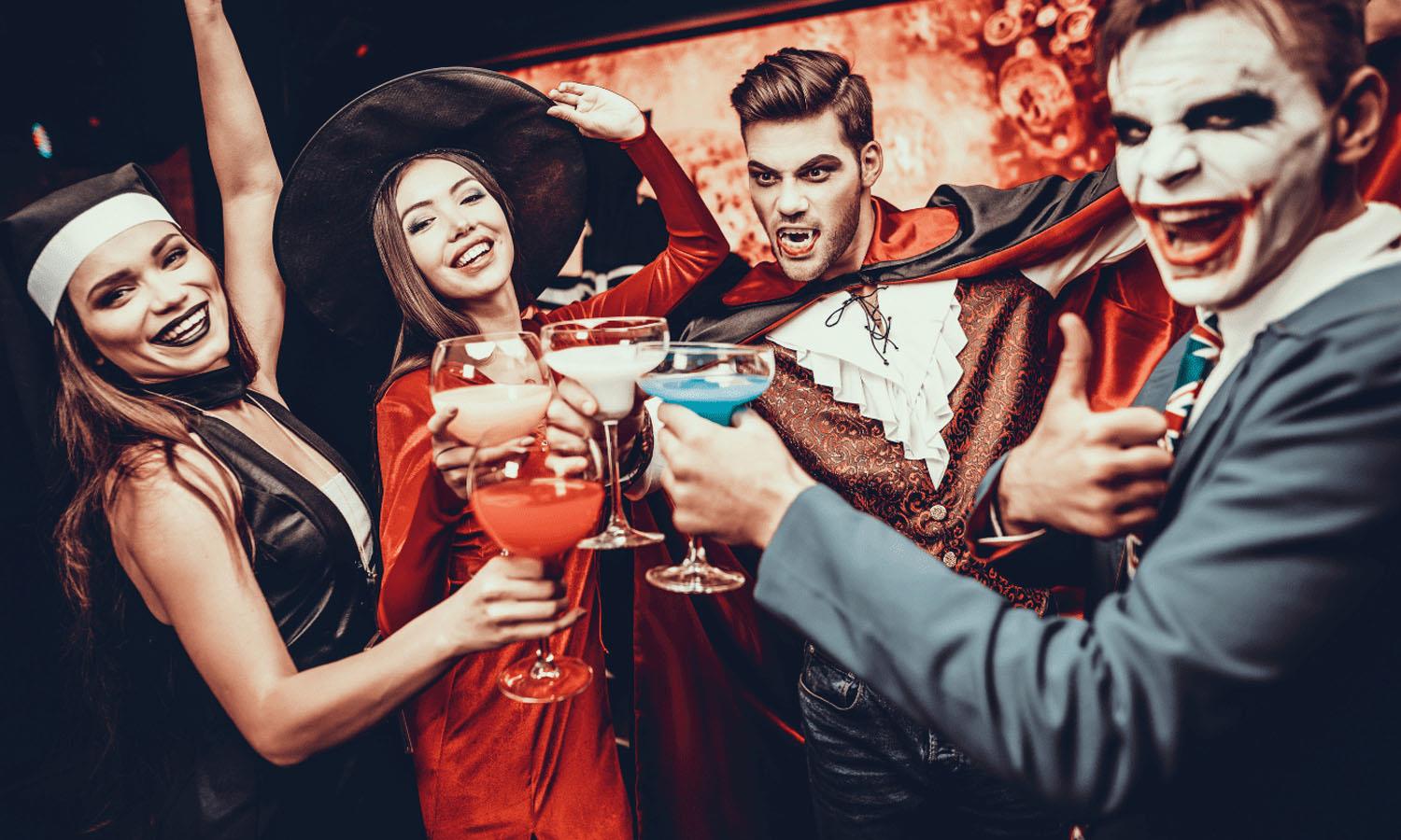 4 people in halloween fancy dress holding drinks