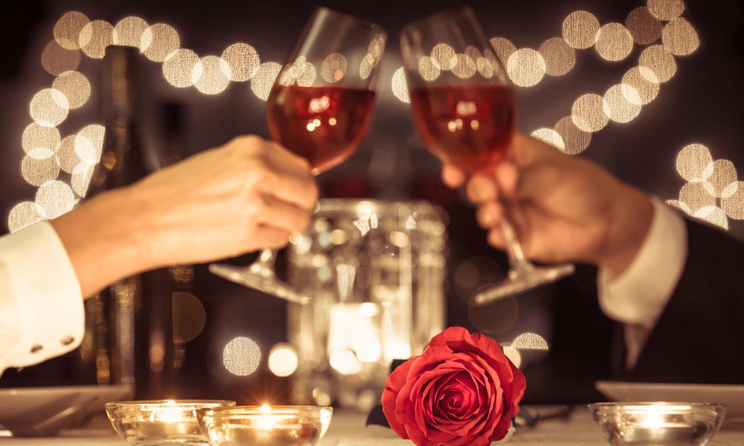 Two glasses being clinked together at table with rose